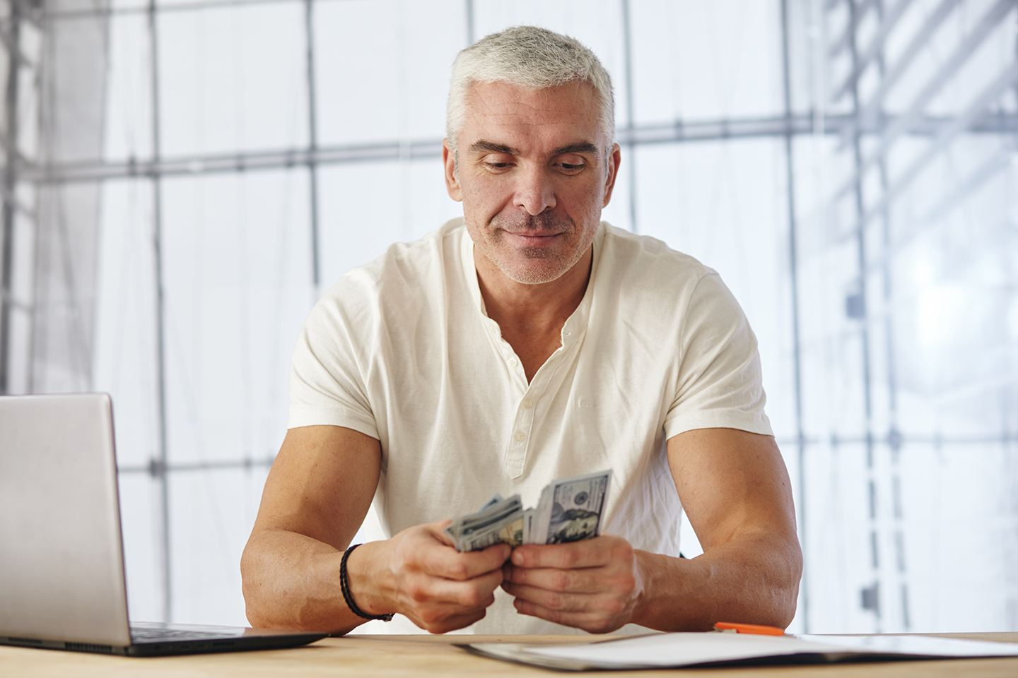 portrait-attractive-caucasian-businessman-working-project-office-desk-with-laptop-paperwork-he-counts-money